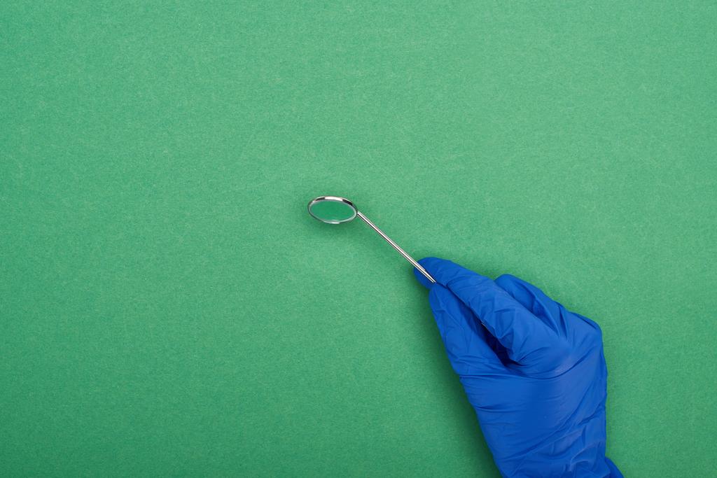 cropped view of dentist in latex glove holding dental mirror isolated on green  - Photo, Image