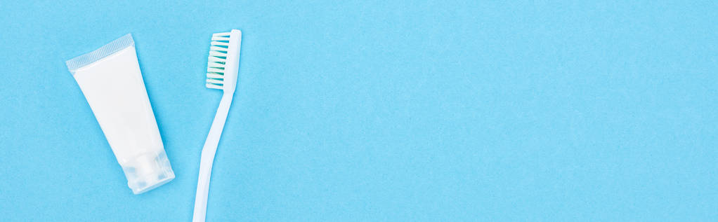 πανοραμική βολή από λευκή οδοντόβουρτσα και οδοντόκρεμα απομονωμένη σε μπλε  - Φωτογραφία, εικόνα