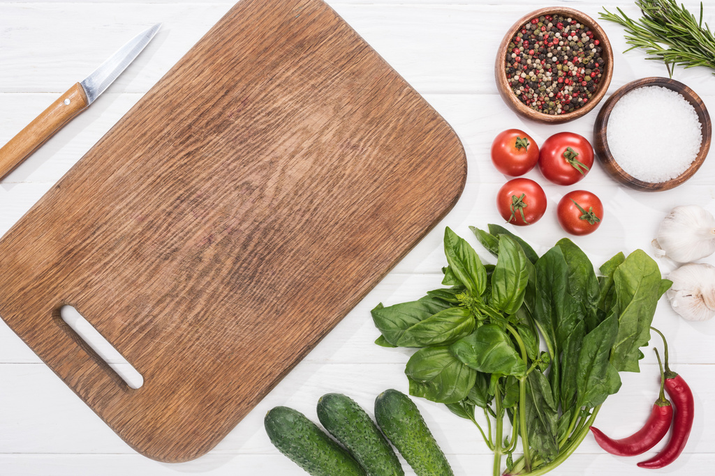 top view of cutting board, cherry tomatoes, greenery, chili peppers, salt, cucumbers, knife, garlics and spices  - Photo, Image