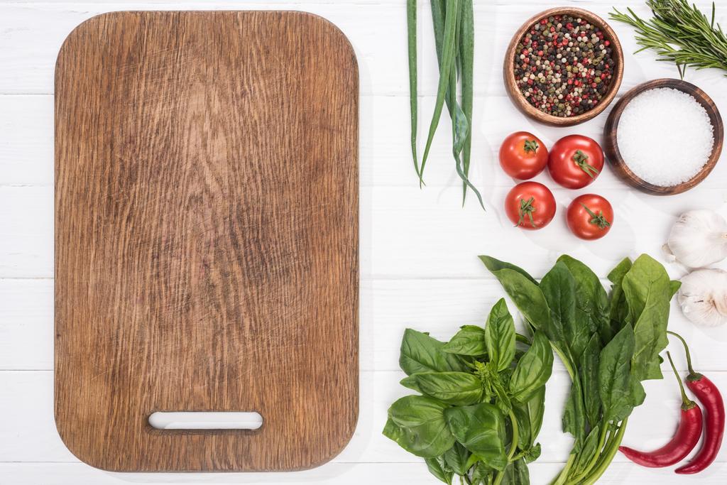 top view of cutting board, cherry tomatoes, greenery, chili peppers, salt, garlics and spices  - Photo, Image