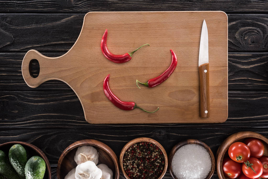 vista superior de tabla de cortar, tomates cherry, sal, ajos, pepinos, cuchillo, chiles y especias
  - Foto, imagen
