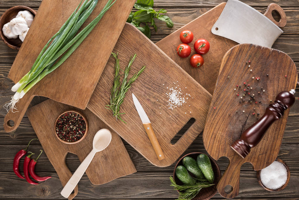 top view of cutting boards, cherry tomatoes, salt, garlics, cucumbers, chili peppers, pepper mill, spoon, meat chopper, knife and spices  - Photo, Image