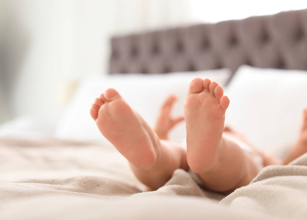 Lindo bebé tendido en la cama, primer plano de las piernas. Espacio para texto
 - Foto, imagen