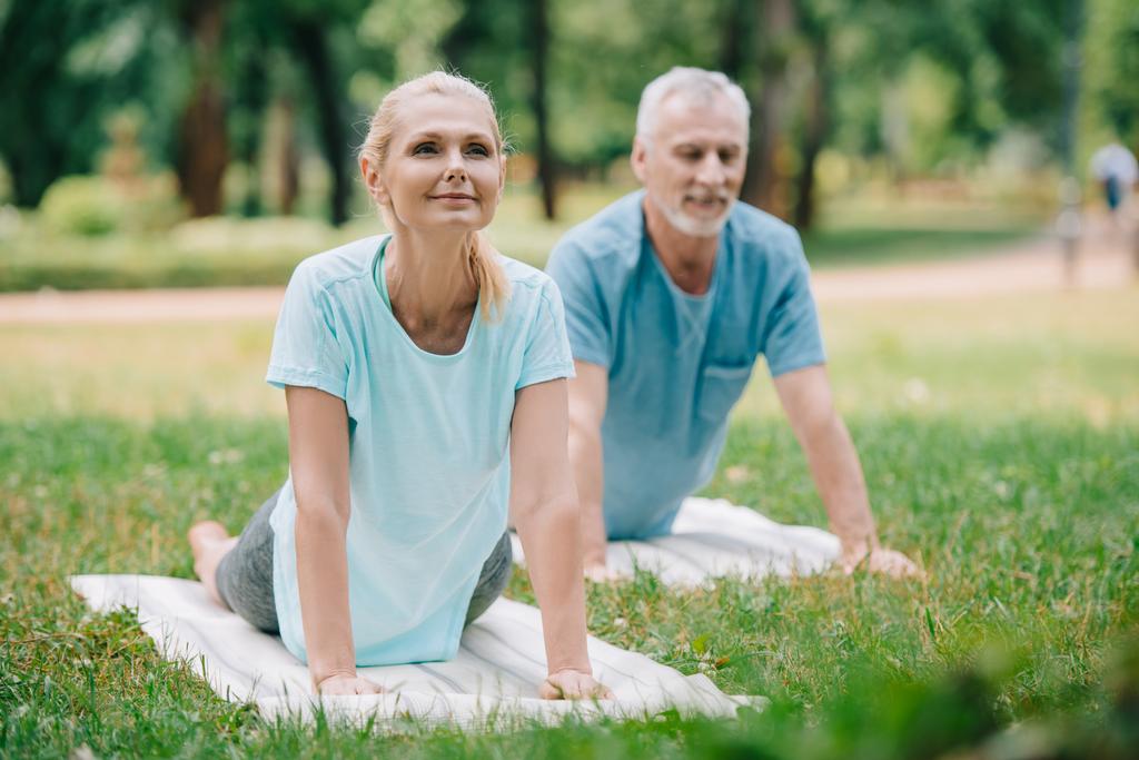 улыбающиеся мужчина и женщина практикующие релаксации йоги позы на циновках йоги
 - Фото, изображение