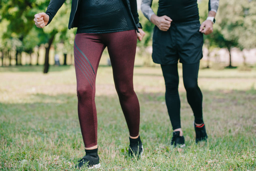 cropped view of mature sportsman and sportswoman jogging in park - Photo, Image