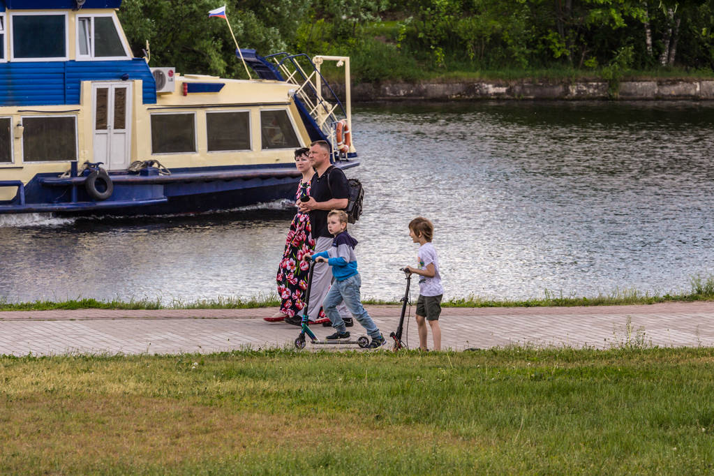 2019.06.01, Moskova, Rusya. Nehir kıyısında scooter kullanan bir çocuk. Bir çocuğun aktif yaşam tarzı. - Fotoğraf, Görsel