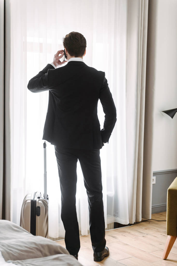 Kuva ajattelu brunette liikemies puhuu matkapuhelin matkatavarat hotellihuoneistossa
 - Valokuva, kuva
