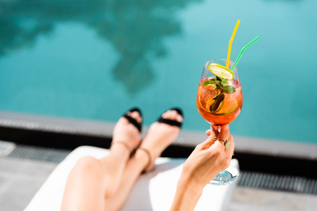 Freigestellter Blick auf Frau in der Nähe von Schwimmbad mit Cocktail auf Resort - Foto, Bild