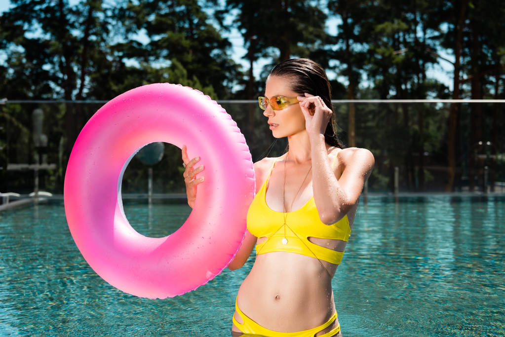 beautiful young woman posing with Swimming Ring in pool on resort - Photo, Image