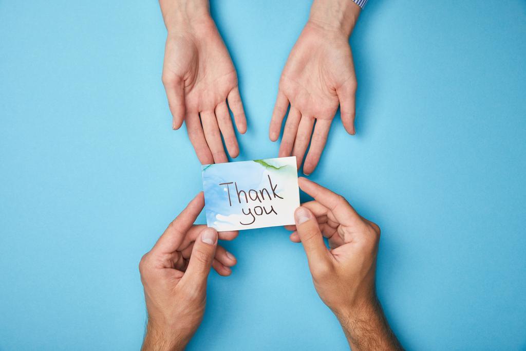 przycięte widok człowieka dając kartkę z życzeniami dziękuję napis do kobiety na niebieskim tle - Zdjęcie, obraz