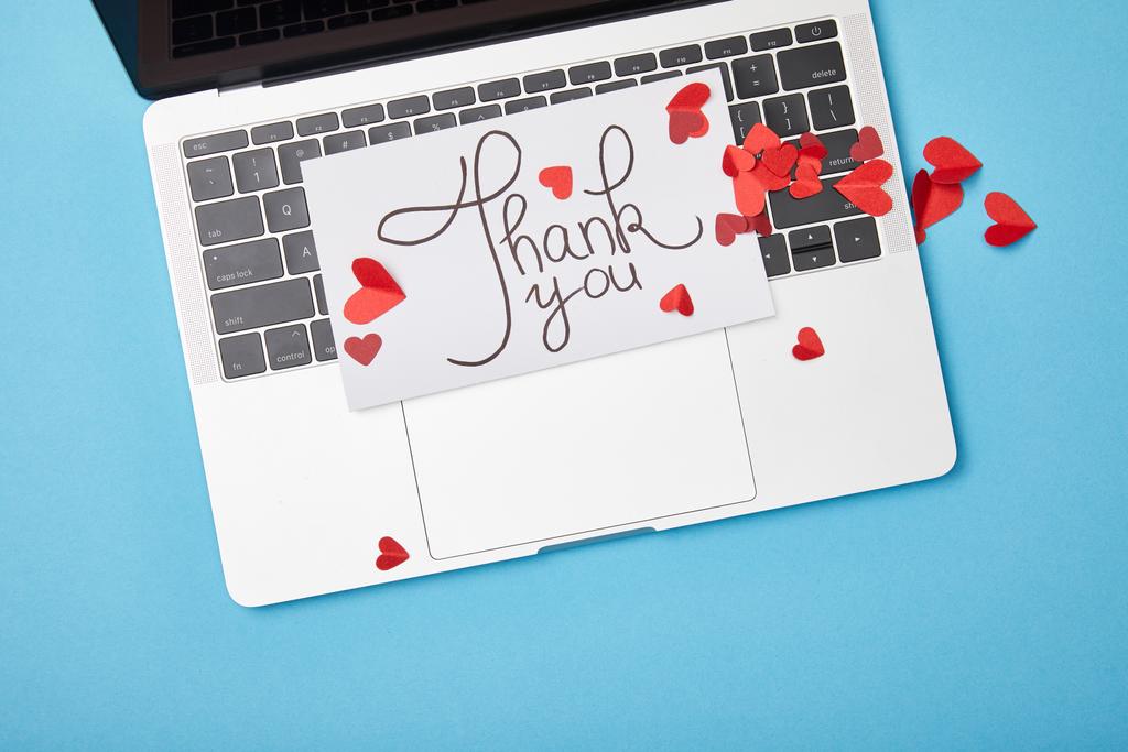 vista superior do laptop e cartão com letras de agradecimento e corações vermelhos de papel no fundo azul
 - Foto, Imagem