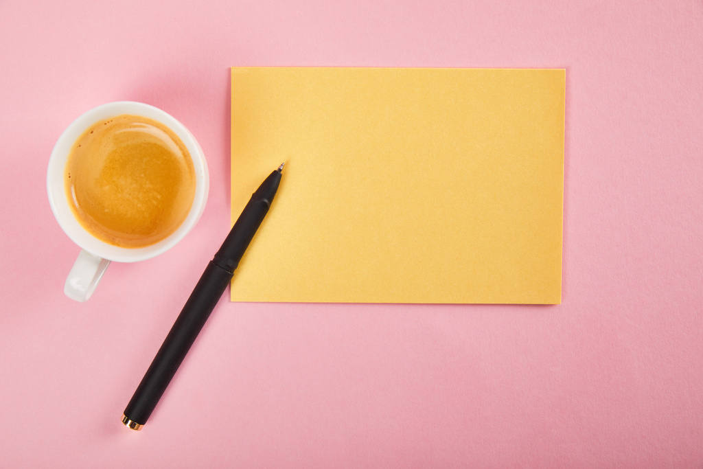 Ansicht des gelben Umschlags mit Stift und Kaffeetasse auf rosa Hintergrund - Foto, Bild