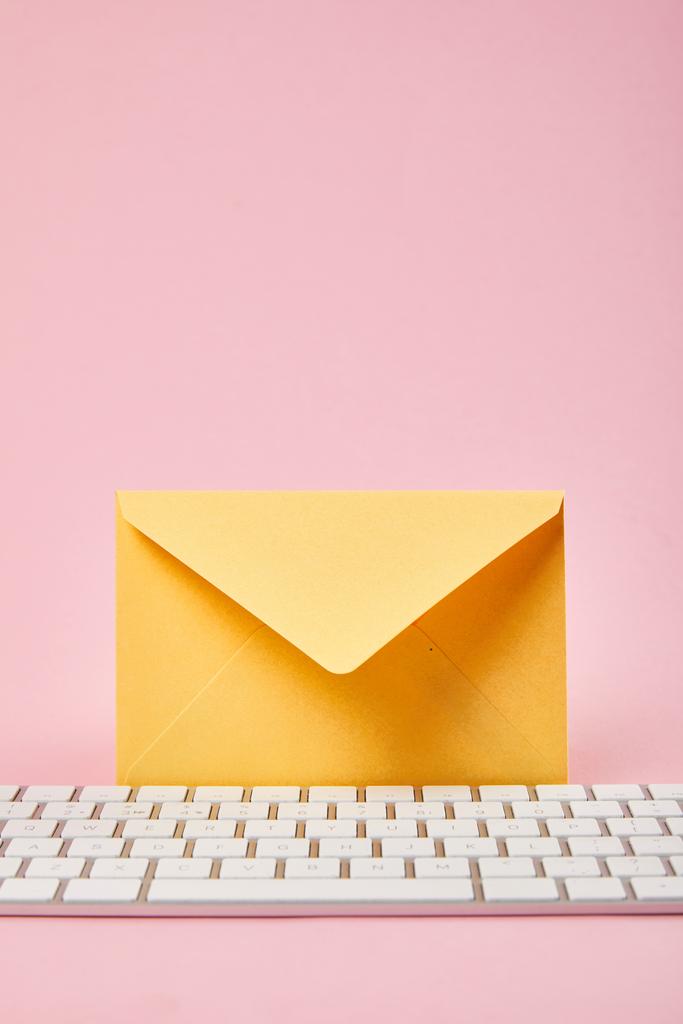 yellow envelope near computer keyboard on pink background - Photo, Image