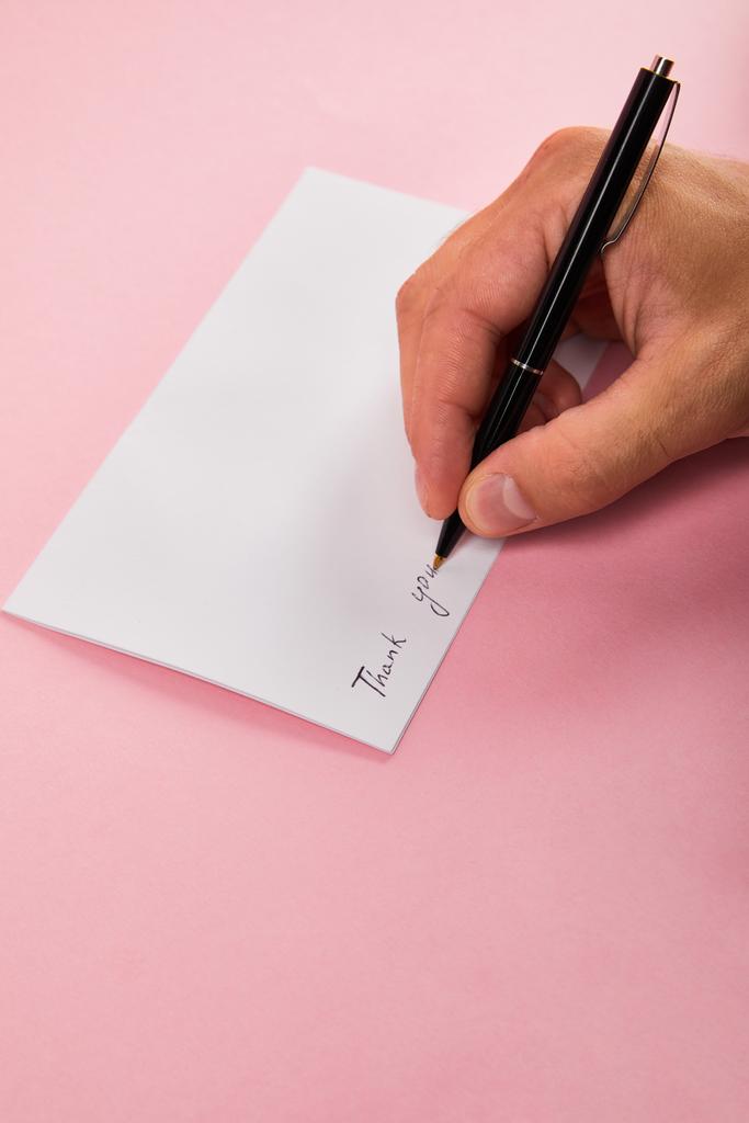 ペンで書く男の部分的なビューは、ピンクの背景に白いカードにレタリングに感謝します - 写真・画像
