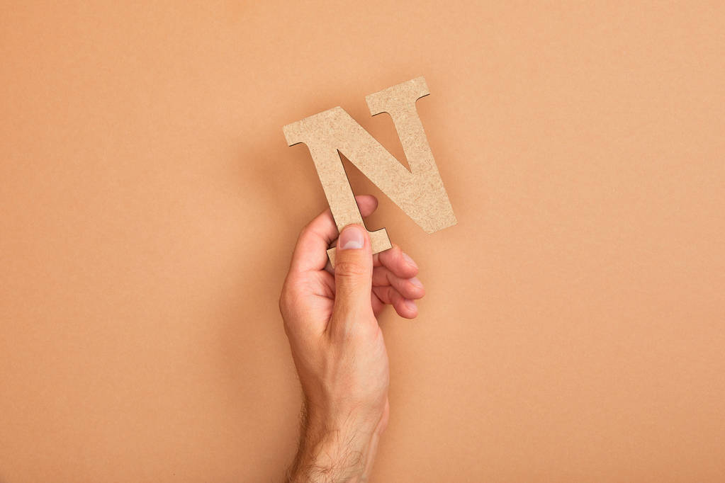 gedeeltelijke weergave van man Holding papier gesneden letter N op beige achtergrond - Foto, afbeelding