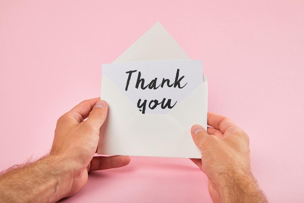 corte vista de homem segurando envelope e cartão branco com palavras de agradecimento no fundo rosa
 - Foto, Imagem