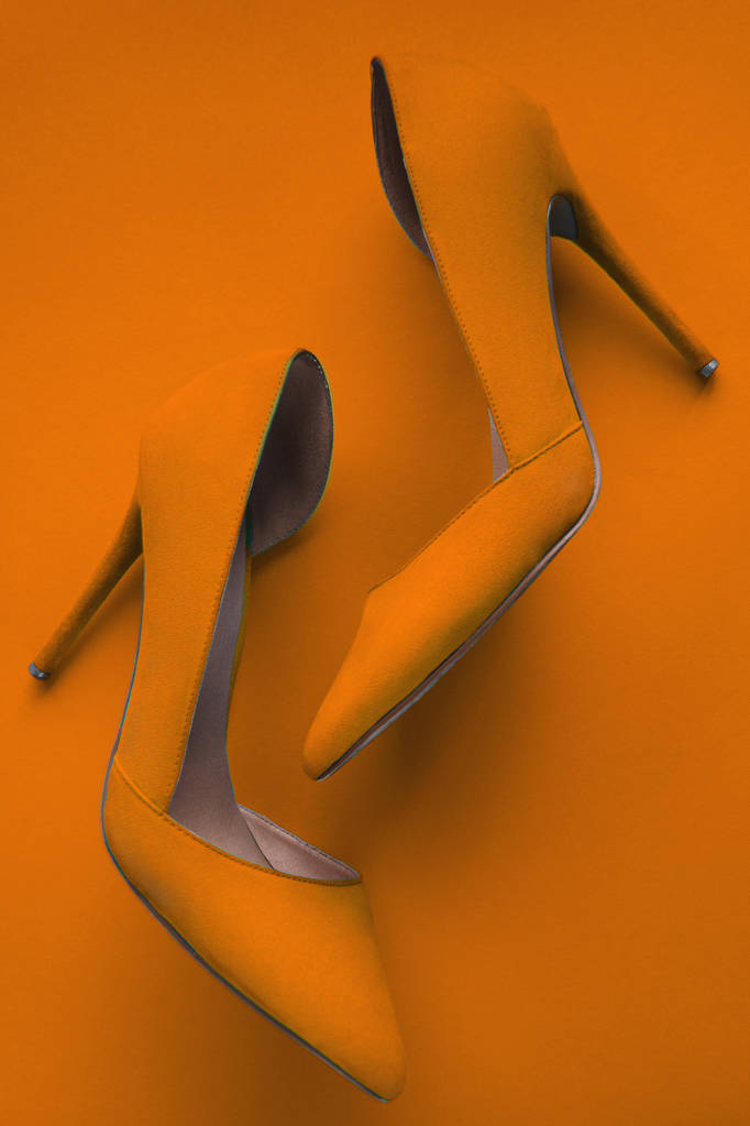 Photo of trendy fancy modern fashionable women luxury orange pair of high heel shoes on a orange background in studio - Photo, Image