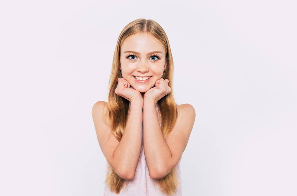 Close up portrait of happy attractive and cute blonde little girl with long hair while she is posing  isolated in studio and smiling - Photo, Image