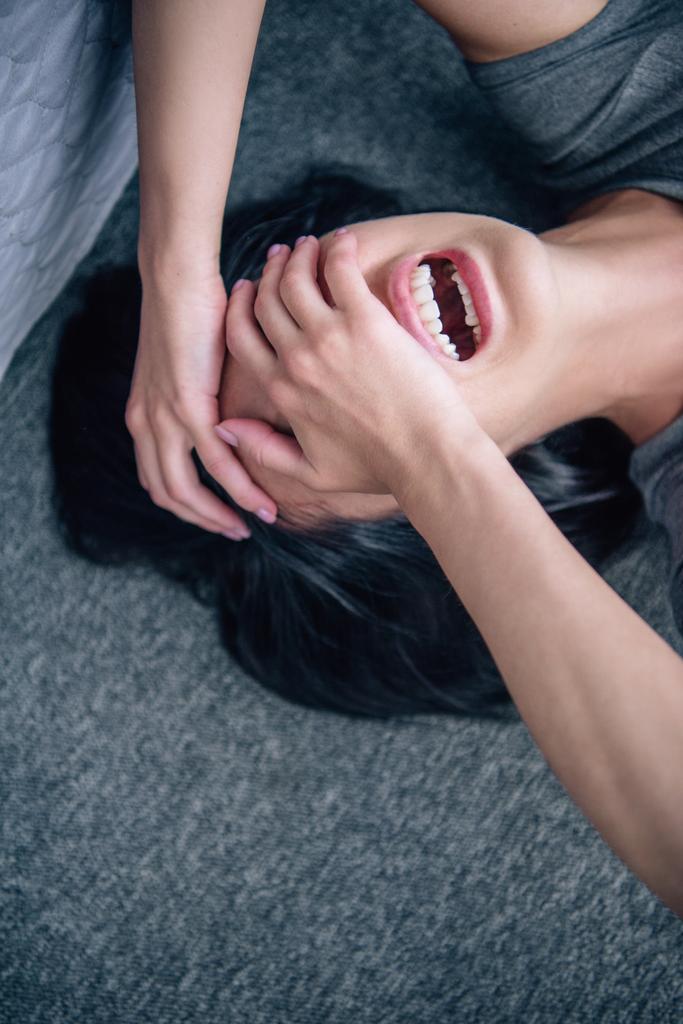 depressieve eenzame brunette vrouw bedekt gezicht met handen en huilen thuis - Foto, afbeelding