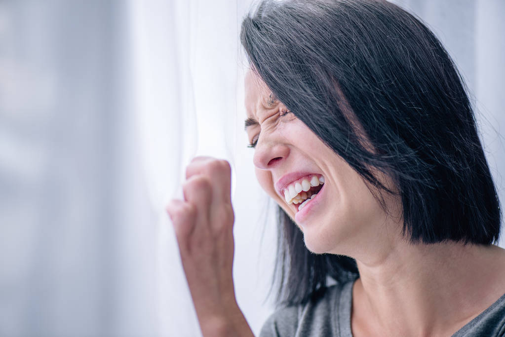 donna bruna depressa che piange vicino alla finestra a casa
 - Foto, immagini