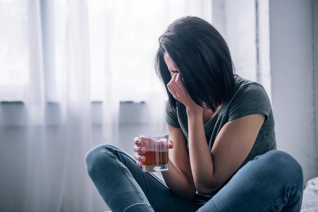 自宅で泣いているウイスキーグラスを持つうつ病の女性 - 写真・画像