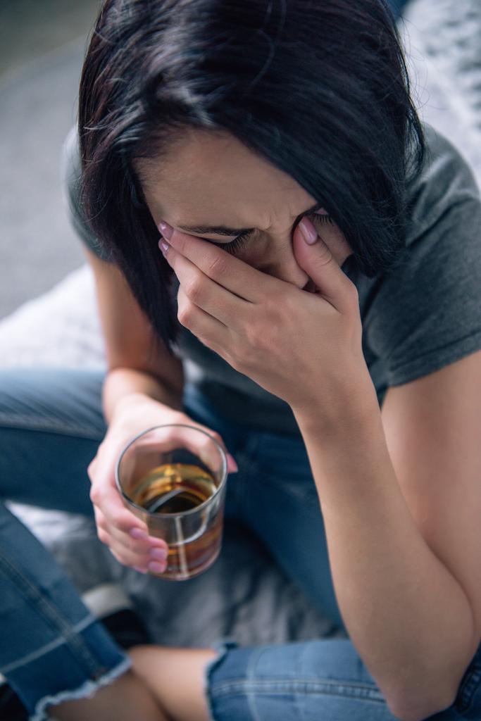 depressieve vrouw met whiskey glas huilen thuis - Foto, afbeelding