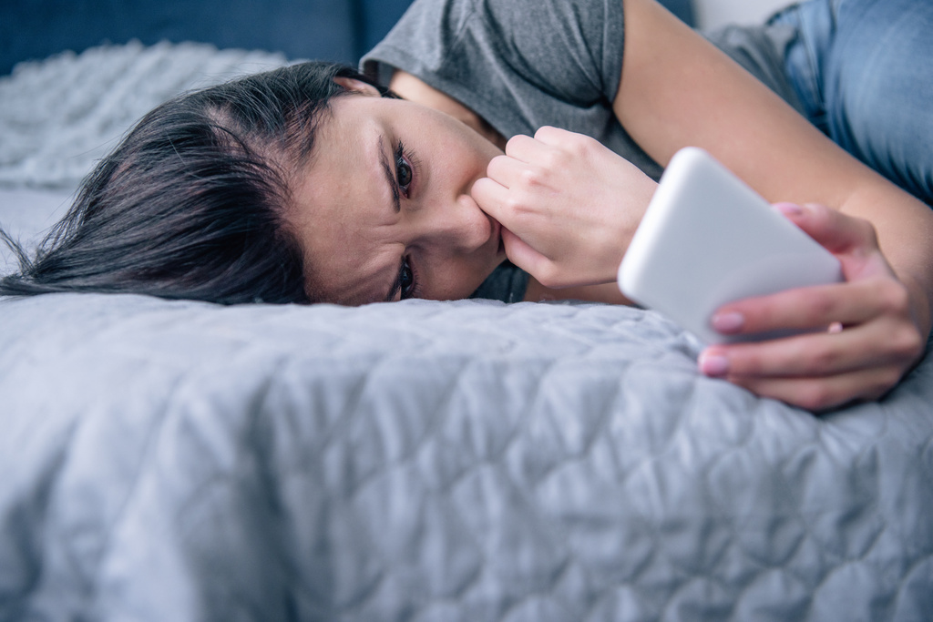 μοναχική αναστατωμένη γυναίκα στο κρεβάτι χρησιμοποιώντας το smartphone στο υπνοδωμάτιο - Φωτογραφία, εικόνα