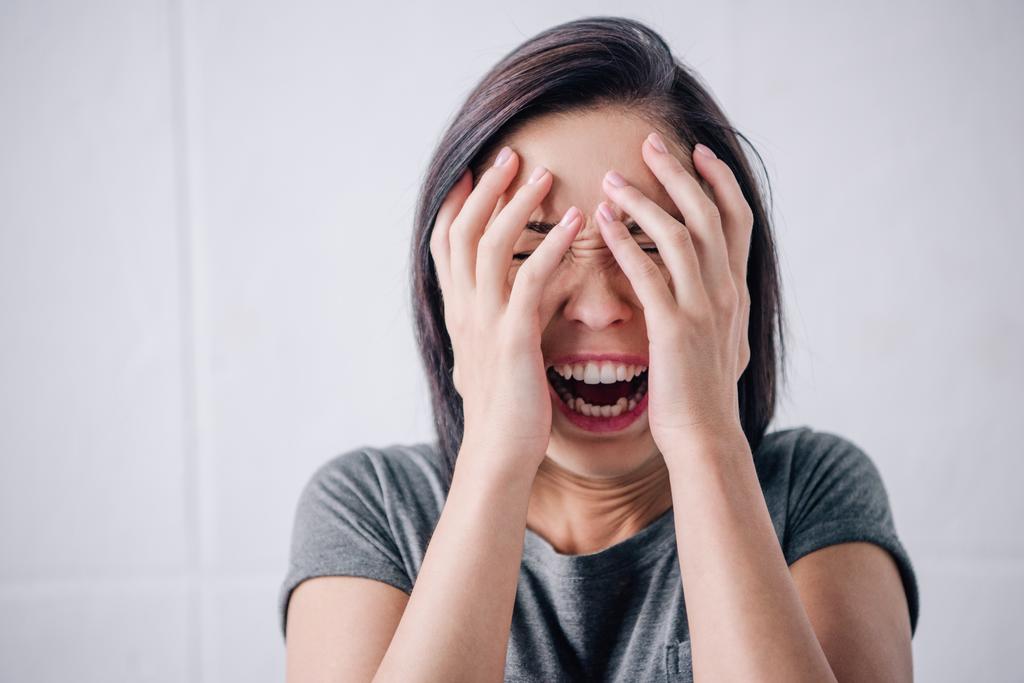boos eenzame brunette vrouw bedekt gezicht met handen thuis - Foto, afbeelding
