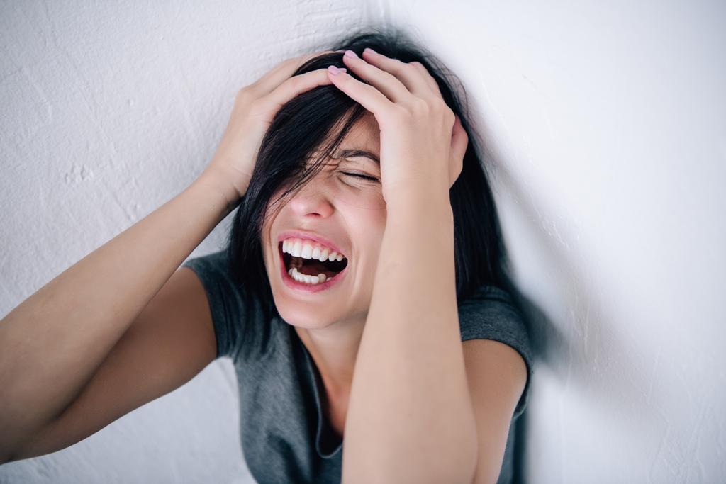 femme brune déprimée avec les mains sur la tête criant à la maison
 - Photo, image