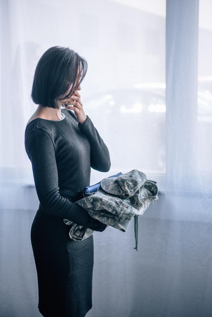 depressed woman holding military clothing at home - Photo, Image