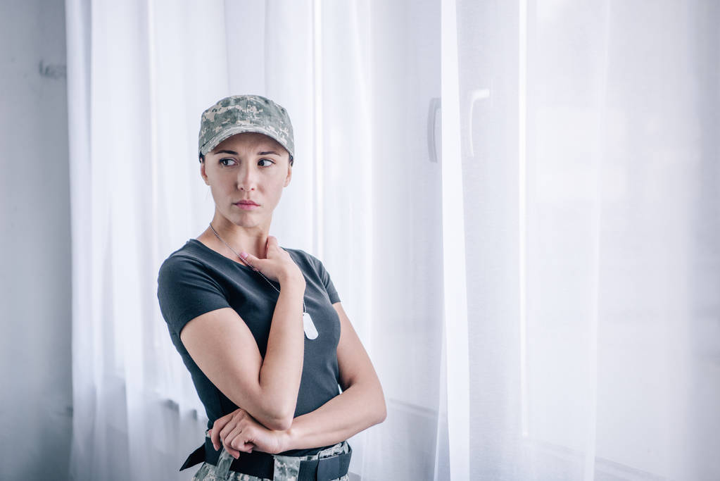 自宅で軍服を着たうつ病の女性が目をそらす  - 写真・画像