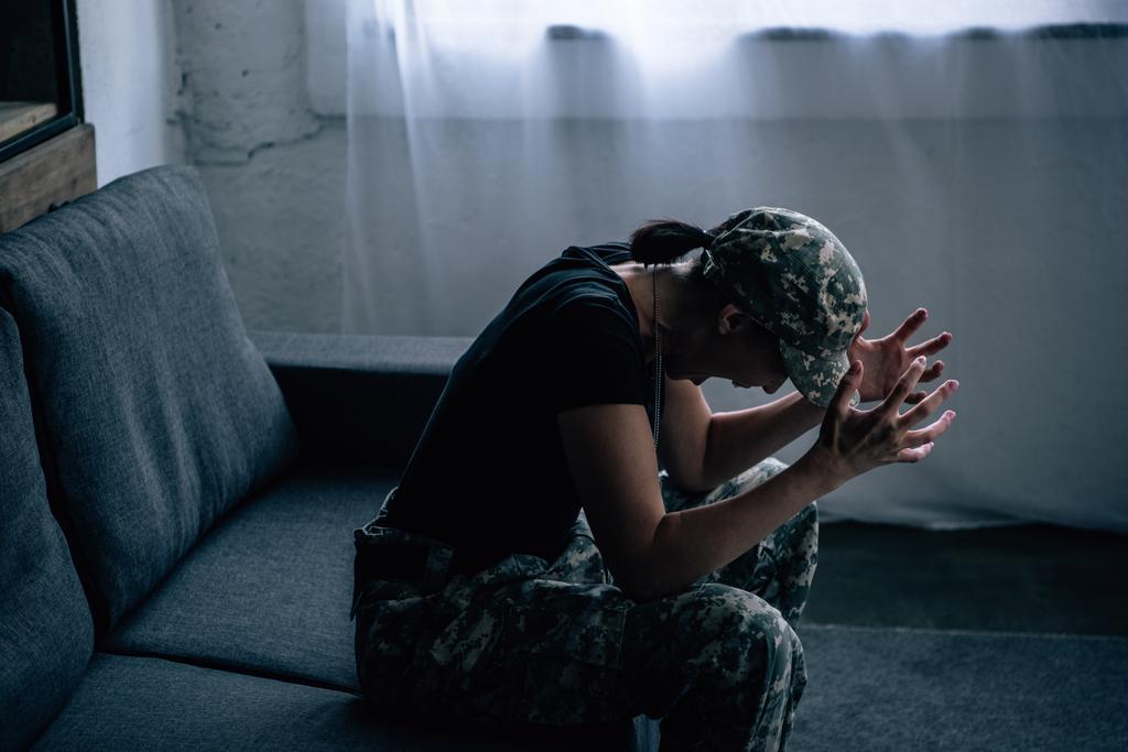 depressieve vrouw in militair uniform schreeuwen thuis - Foto, afbeelding