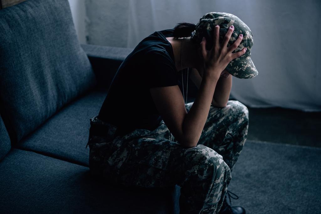 mujer deprimida en uniforme militar con las manos en la cabeza en casa
 - Foto, imagen