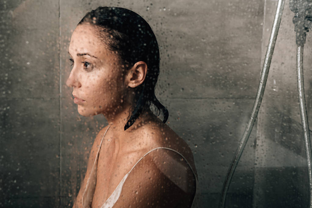 beautiful sad woman in shower at home through glass with water drops - Foto, afbeelding
