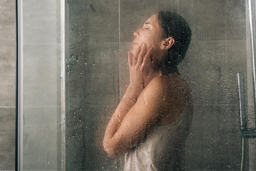 sad depressed woman in shower through glass with water drops - Foto, afbeelding