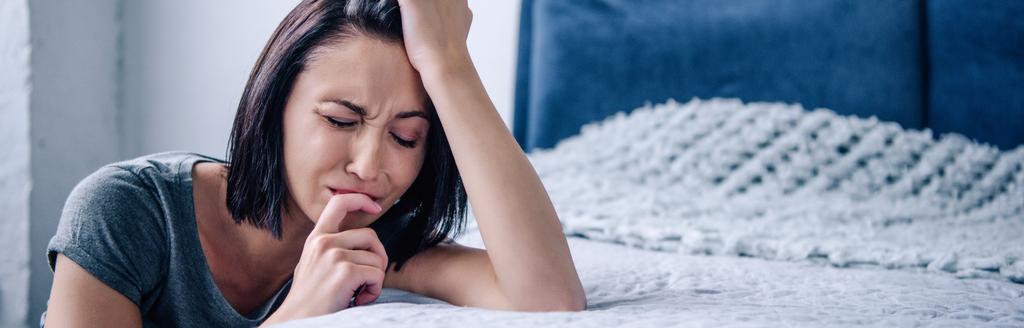 panoraama laukaus masentunut brunette nainen itkee lähellä sänkyä kotona
 - Valokuva, kuva
