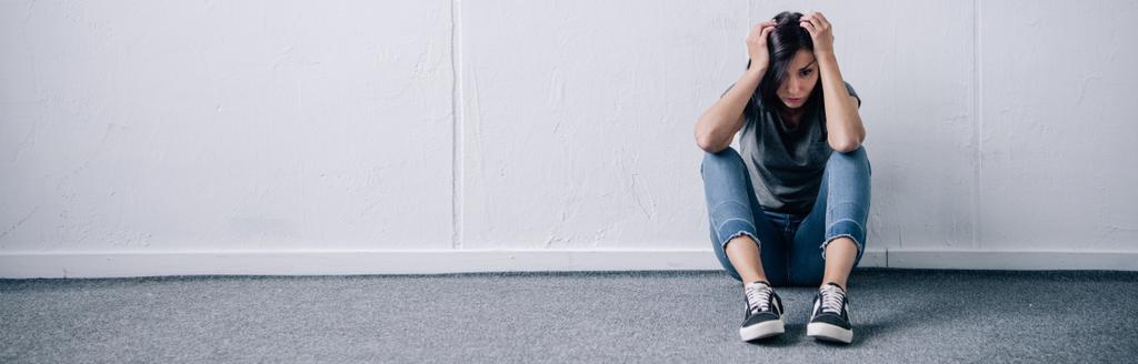 colpo panoramico di donna bruna depressa seduta sul pavimento a casa con spazio copia
 - Foto, immagini