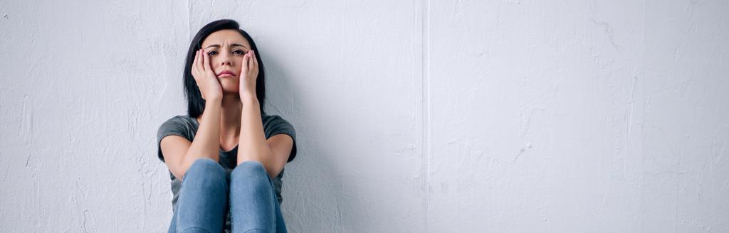 colpo panoramico di donna bruna depressa seduta sul pavimento a casa
 - Foto, immagini