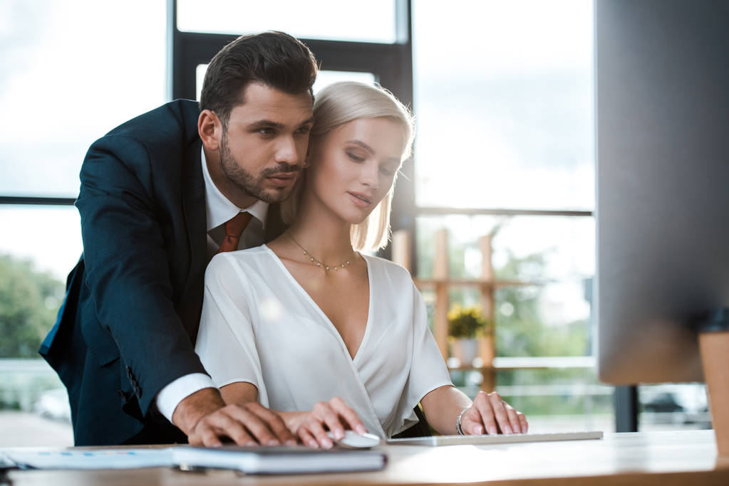 selective focus of bearded businessman in suit standing near attractive blonde girl in office  - Photo, Image