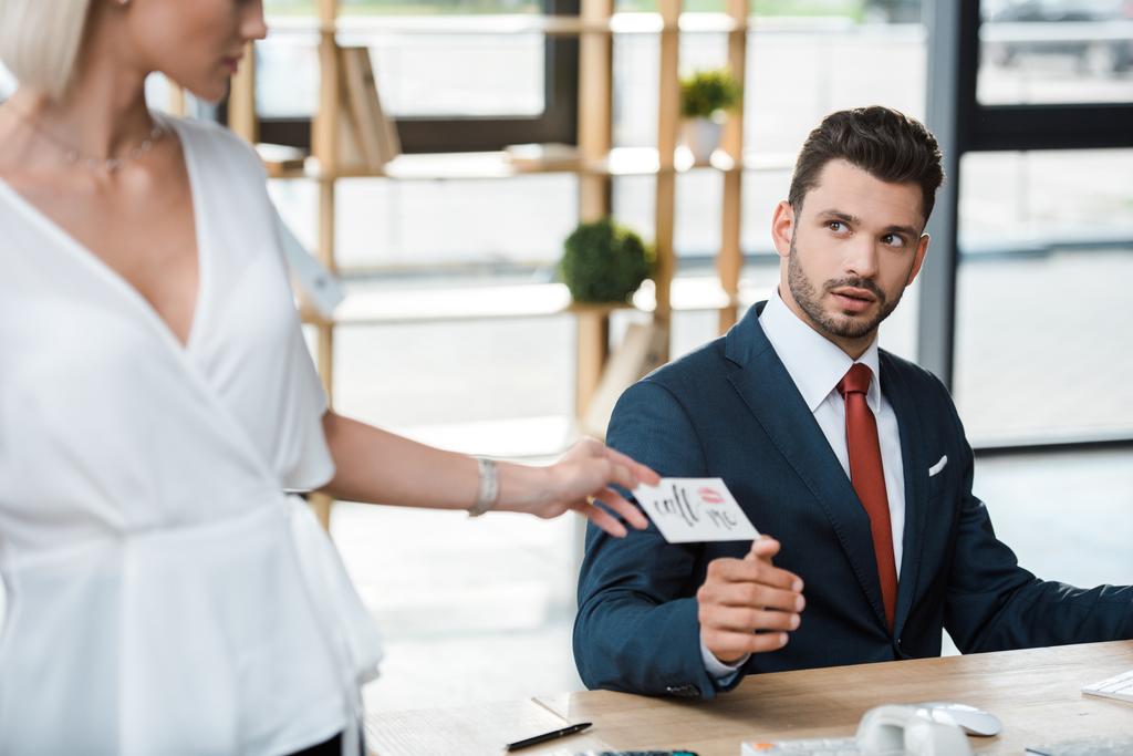 recortado vista de mujer rubia sosteniendo tarjeta con me llaman letras cerca sorprendido hombre de negocios
  - Foto, Imagen