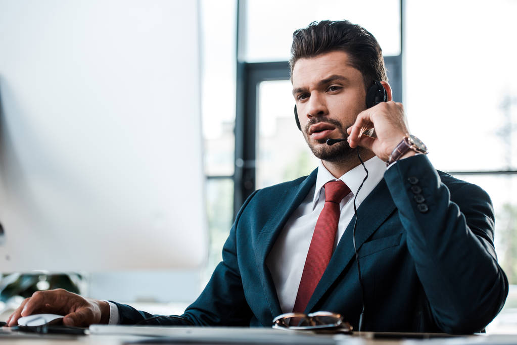 красивый бизнесмен трогает микрофон, сидя в офисе
  - Фото, изображение