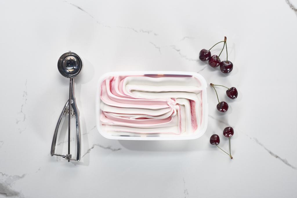 a fagylaltkanál, a cseresznye és a jégkrém, a márvány szürke hátterének felülnézete - Fotó, kép