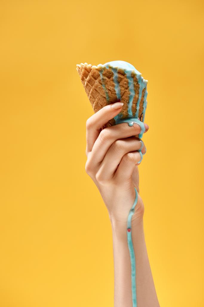 vista cortada de mulher segurando delicioso sorvete azul derretido em cone de waffle crocante isolado no amarelo
 - Foto, Imagem
