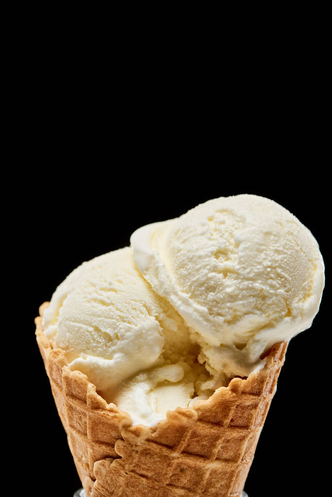 vista de perto de delicioso sorvete de baunilha em cone de waffle crocante isolado em preto
  - Foto, Imagem