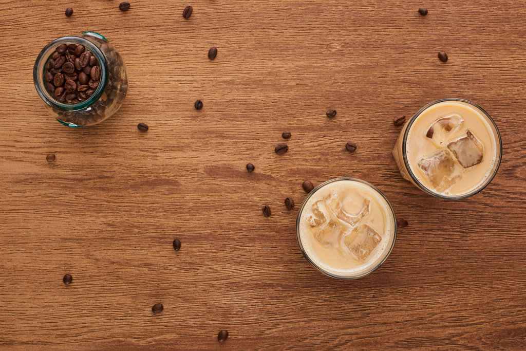 top view of ice coffee and coffee grains on wooden table - Photo, Image