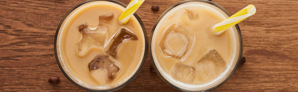 вид сверху на свежий ледяной кофе в стаканах с соломинками и зерном кофе на деревянном столе, панорамный снимок
 - Фото, изображение