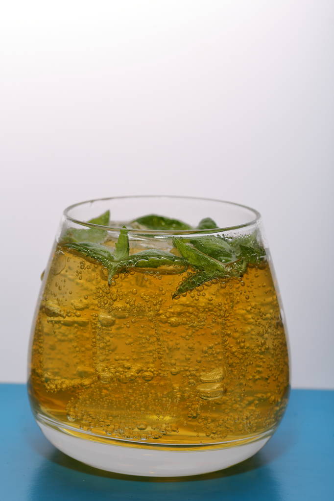 Refreshing drink with gas bubbles. Nalit in a transparent glass. It laid crushed ice. Decorated with mint leaves. - Photo, Image