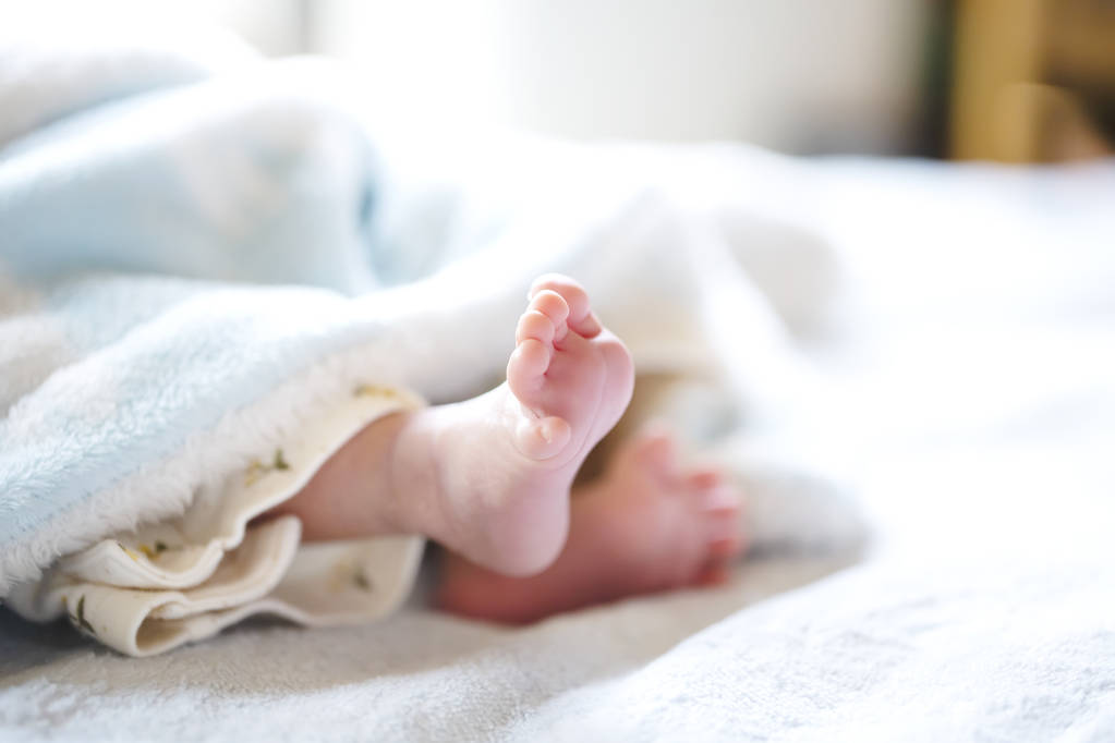 Újszülött egy fehér és világoskék takaró-apró Baby lábak. - Fotó, kép