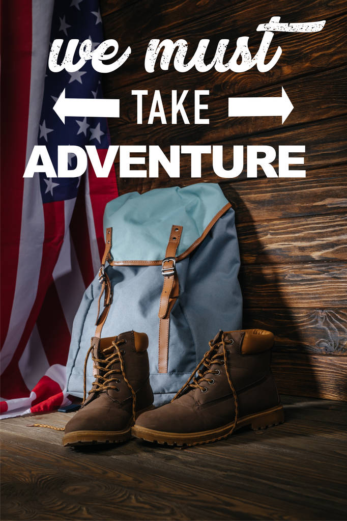 Trekkingstiefel, Rucksack und amerikanische Flagge auf Holzuntergrund mit Abenteuerabbildung  - Foto, Bild