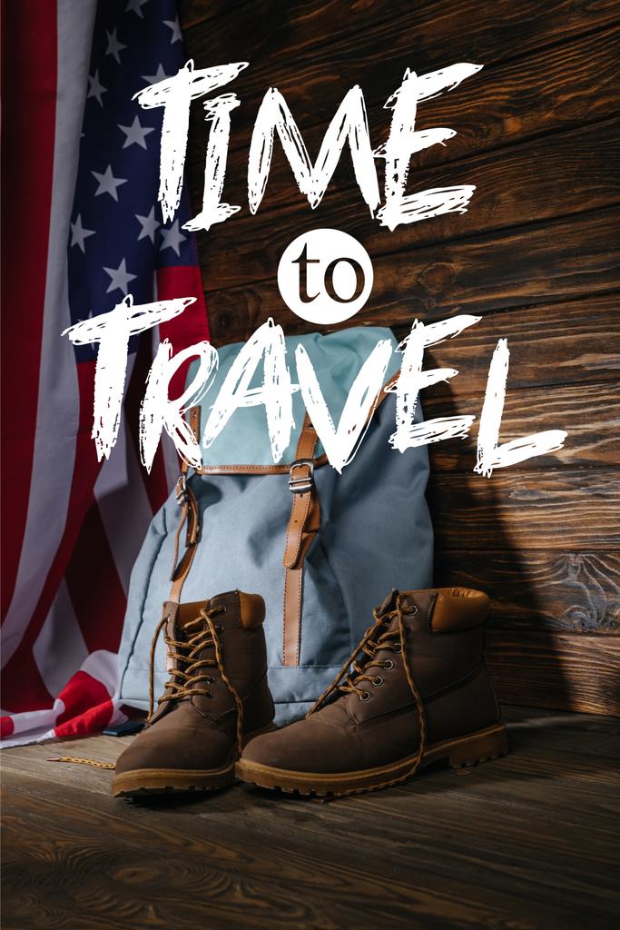 trekking laarzen, rugzak en Amerikaanse vlag op houten oppervlak met tijd om te reizen illustratie - Foto, afbeelding